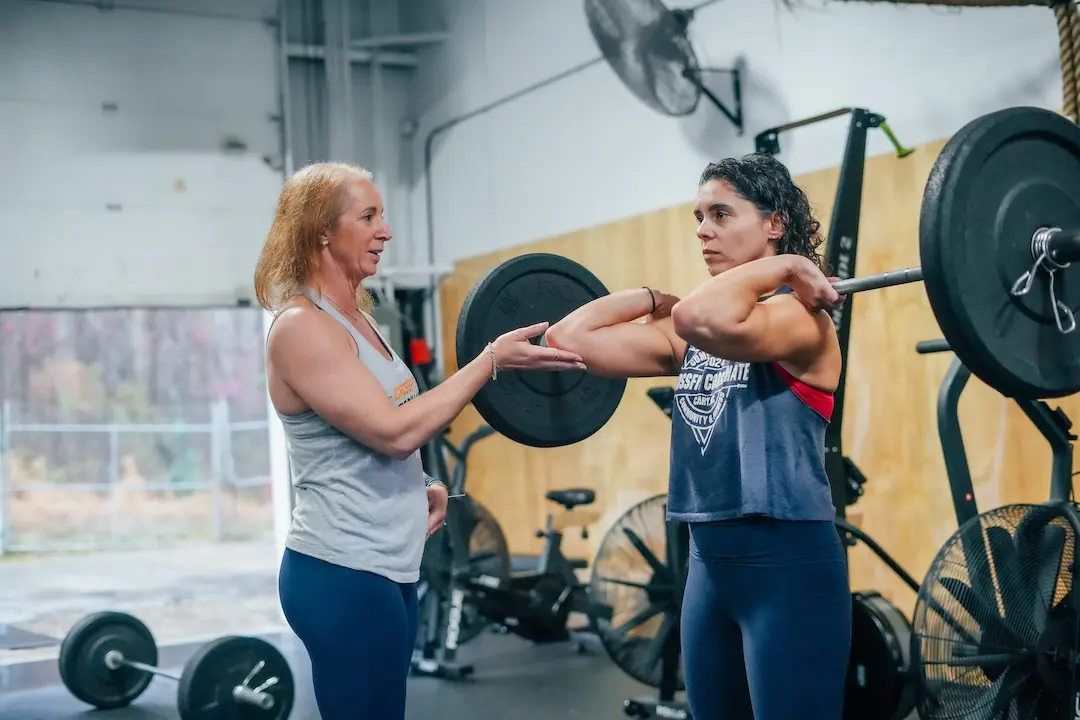 Coach guiding a member through a barbell lift at CrossFit Coordinate in Cary, NC