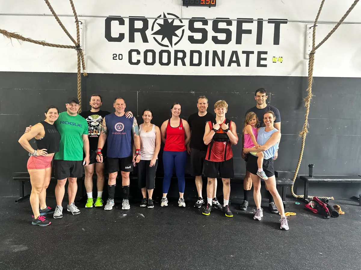 CrossFit Coordinate members and their families gathered together under the CrossFit Coordinate logo after Memorial Day Murph in Cary, NC