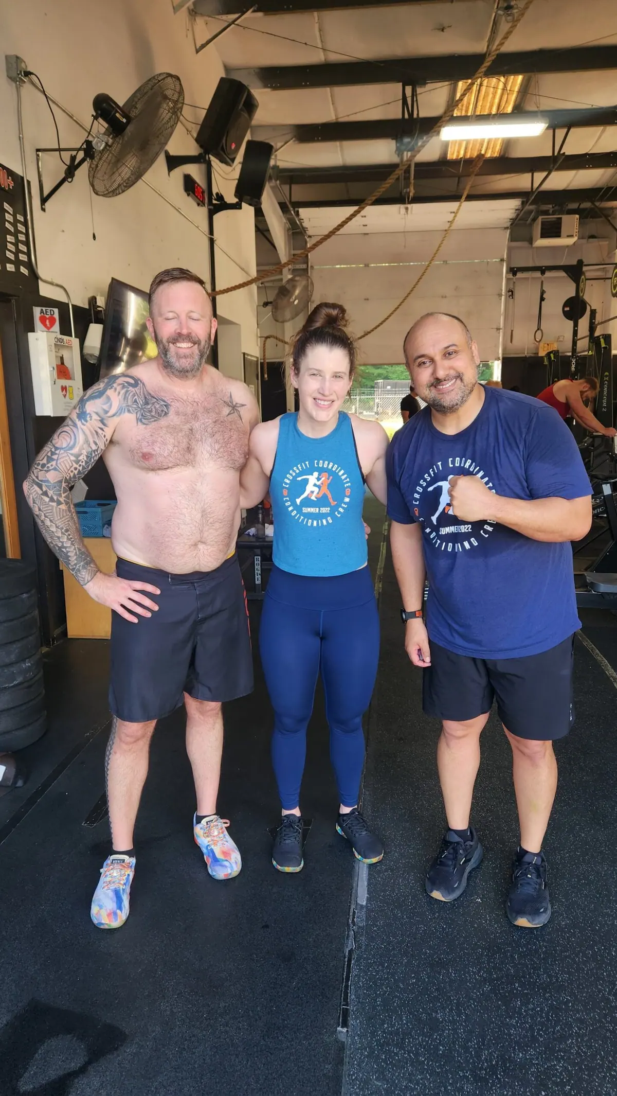 Three teammates flexing and smiling mid-event during the 2026 Ergathlon at CrossFit Coordinate