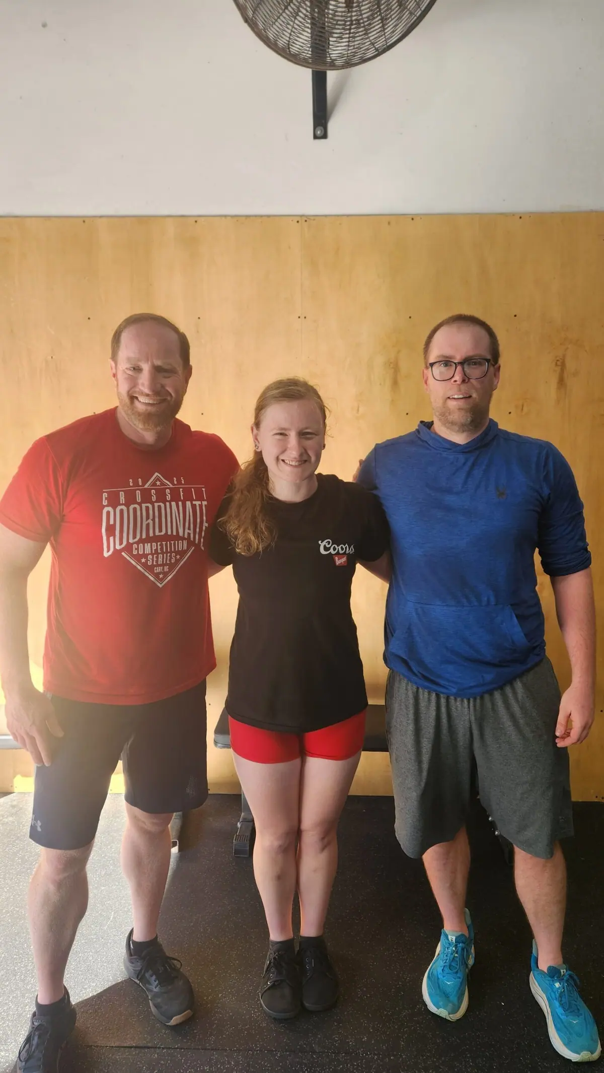 A three-person Ergathlon team in team gear, posing on the gym floor before their heat starts