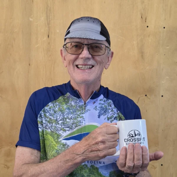 Heinz in a cycling jersey holding a CrossFit Coordinate mug.